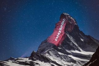 A light projection on to the side of a mountain with the message #stayhome