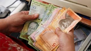 A cashier counts Venezuelan bolivar notes at a supermarket checkout line in Caracas (20/10/2015)