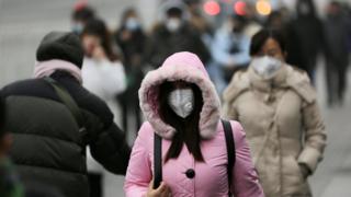 12月21日,北京街头,一处办公区域附近戴口罩的行人。