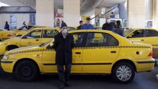 سائق أجرة في ايران يضع قناعاً طبياً لتجنب الإصابة بفيروس كورونا