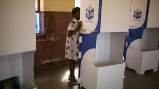 A girl watches while her mother marks her ballot at at a polling station at the Sheshego township, on the outskirts of Polokwane on May 8, 2019.