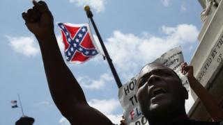 Man protests before a Confederate flag