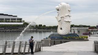 Одинокий мужчина у статуи Мерлиона в Сингапуре