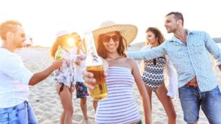Holidaymakers on beach with drinks