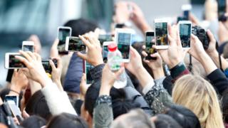 Gente sacando fotos con sus teléfonos