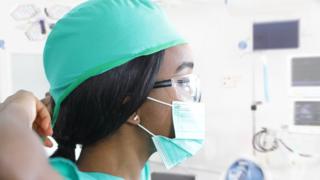 A medical worker puts on a protective mask