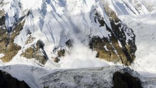 An avalanche of ice rushes down an ice slope