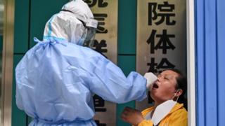 Le 13 mai 2020, un travailleur médical prélève un échantillon sur une femme pour tester le nouveau coronavirus COVID-19 à Wuhan, dans la province centrale du Hubei en Chine.