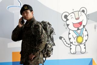 平昌冬季五輪の宣伝ブースの前で携帯電話を使う韓国軍兵士(5日、韓国・ソウル)