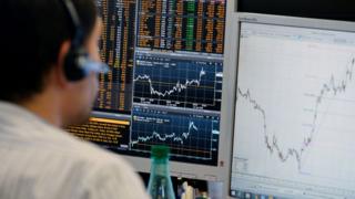 A trader checks his screens at investment bank Saxo Banque in Paris