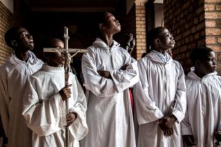 Altar boys try to get a glimpse at the current President of the Democratic Republic of the Congo, Felix Tshisekedi, ahead of a mass at the Notre dame de Kinshasa to commemorate the death of his father, Etienne Tshisekedi on February 1, 2019 in Kinshasa.