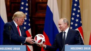 El presidente de Rusia, Vladimir Putin (der.), le entrega un balón de fútbol del Mundial al presidente de EE.UU., Donald Trump durante la cumbre en Helsinki.