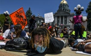 Multidão participa de de uma manifestação ao lado do Capitólio do Estado do Colorado com as mãos atadas nas costas