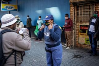 A policewoman shows someone how to put their mask on