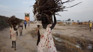 A young woman carries firewood after returning to the United Nations base outside Bentiu, at the end of the day, on 20 September 2015.