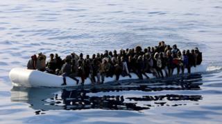 Мигранты видны в резиновой лодке, когда их спасают ливийские береговые охранники у побережья Ливии, 15 января 2015 г.