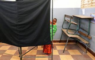 A woman carries a child as she casts her vote during the presidential election, at a polling station in Medina neighbourhood, Dakar, Senegal February 24, 2019