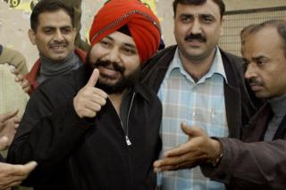 Далер Менди показывает на фотографов, когда он прибывает в суд Дели 20 декабря 2003 года.