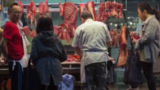 Pessoas compram carne em açougue em Hong Kong