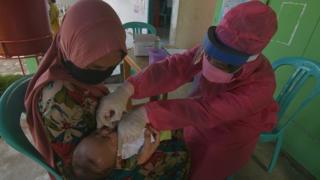 A health worker gives a vaccine to a child in Indonesia