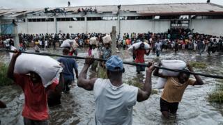 People take sacks of Chinese rice printed "China Aid" from a warehouse surrounded by water after cyclone hit in Beira, Mozambique, on March 20, 2019