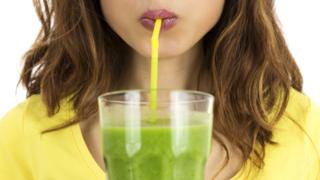 Joven tomando un licuado verde