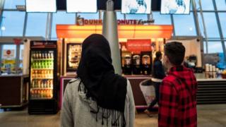 A young woman in a Hijab watches the arrivals board at New York's JFK airport