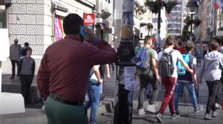 čovek razgovara telefonom naslonjen na banderu