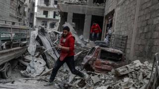 A red crescent volunteer runs after bombing, rebels-held Douma, Eastern Ghouta, Syria, 22 February 2018.
