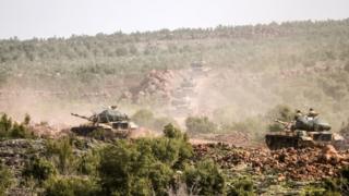 Turkish troops advance near Syrian border throw bush landscape