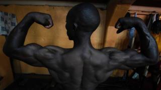 Shi kuwa wannan mutumin da ke gwada kwanjinsa yana kallon kansa a madubi bayan ya gama motsa jiki a Kampala, babban birnin Uganda...