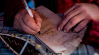 Homem escreve em pedaço de papel