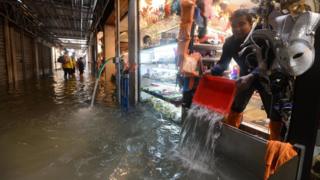 A trader empties water from his store in Venice on October 29, 2018