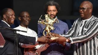 Le réalisateur franco-sénégalais, Alain Gomis, reçoit l'Etalon d'Or du Yennenga des mains des présidents Roch Marc Christian Kabore (droite) du Burkina Faso et Alassane Dramane Ouattara (gauche) de Côte d'Ivoire