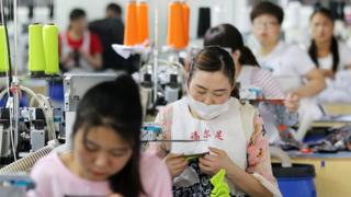 Китайские сотрудники работают над носками, которые будут экспортированы на заводе в Хуайбэй в китайской провинции Аньхой 22 июня 2018 года.