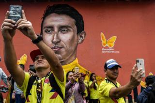 People make selfies with a mural depicting Colombia's Tour de France winner Egan Bernal after arrival in his hometown Zipaquira, Cundinamarca, Colombia