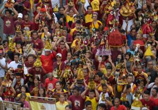Catholics holds up a replica of the Black Nazarene at a blessing in Manila (7 Jan 2019)