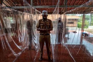 People pray between plastic separation curtains