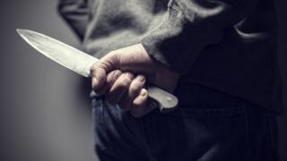 Man with a knife behind his back