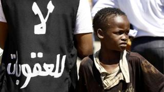 Суданский мальчик демонстрирует у здания посольства США в столице страны Хартуме 3 ноября 2015 года протест против санкций, введенных против их страны Соединенными Штатами. Судан находится под торговым эмбарго США с 1997 года, наложенным на нарушения прав и поддержку радикальных исламистских групп в начале 1990-х годов.