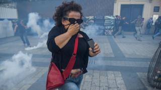 A woman runs from tear gas on the Champs Elysees