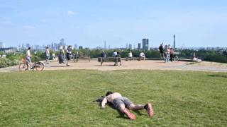 A man sunbathes on Primrose Hill in London on May 7, 2020 as life continues in Britain under a nationwise lockdown to slow the spread of the novel coronavirus