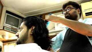सैलुनमा कपाल काट्दै