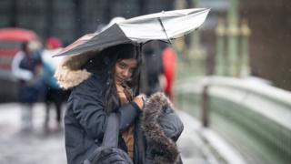 A woman on Westminster bridge holding a broken umbrella above her head