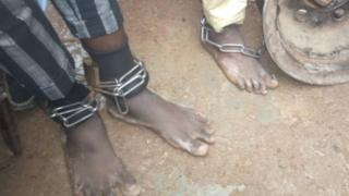 Captives are seen with chains around their ankles as police free them