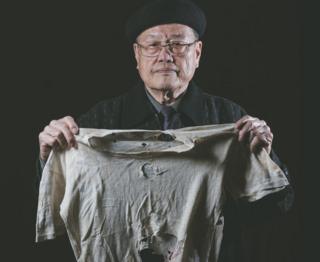 潘信行依旧保存着父亲受刑时所穿、被弹孔穿过的衣服。
