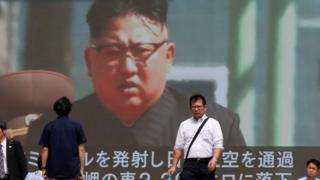 Passersby walk past a TV screen reporting news about North Korea's missile launch in Tokyo, Japan on 15 September 2017.