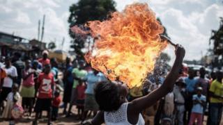 A member of Kenyan acrobat group Kibera Messenger breathes fire during a performance for filming in Kibera, Nairobi, on March 7, 2018.