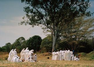 Group of people dressed in white next to a tree