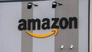 The Amazon logo is seen on the exterior steel cladding of an industrial building in this close-up shot